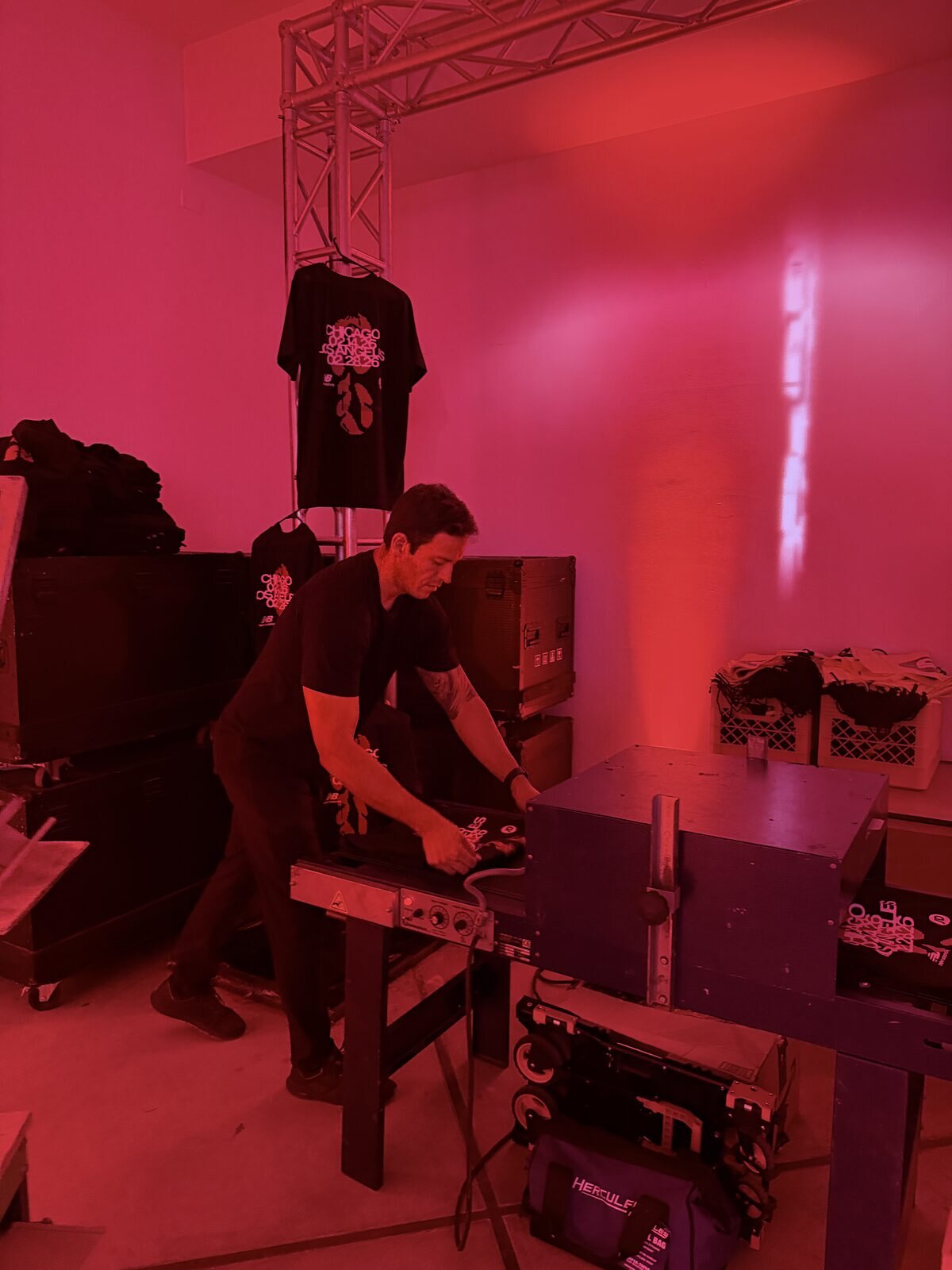 Crew member running garments through a conveyor dryer backstage at a company event