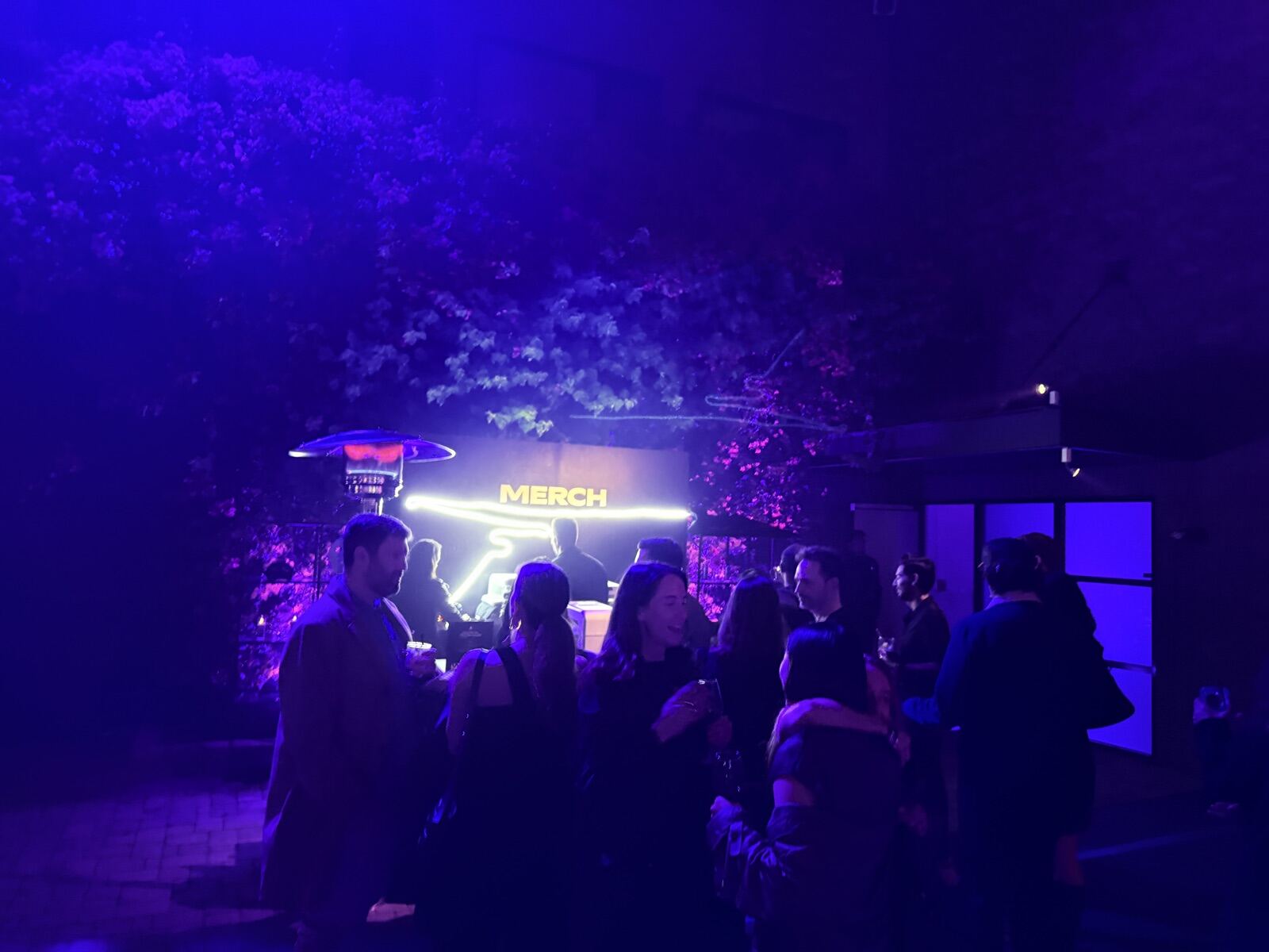 Illuminated merch booth at an evening company party under blue lighting